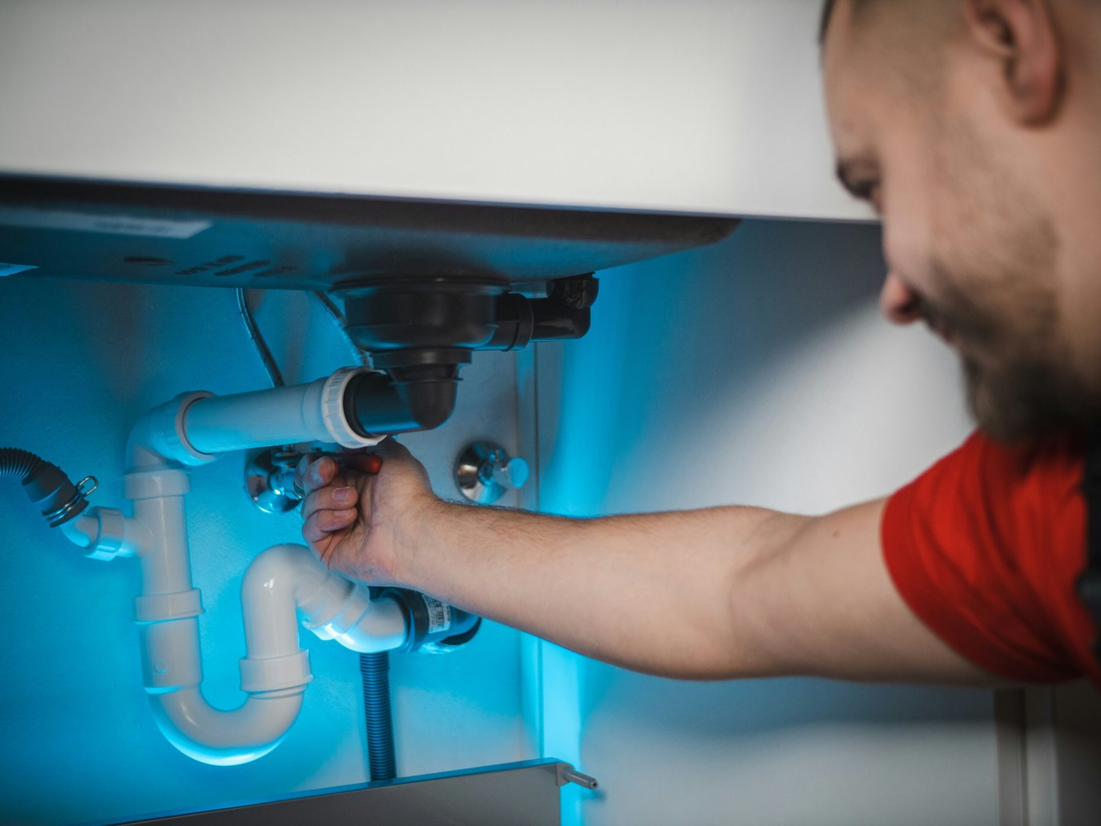 Plumber repairing a pipe under a sink in a Houston home